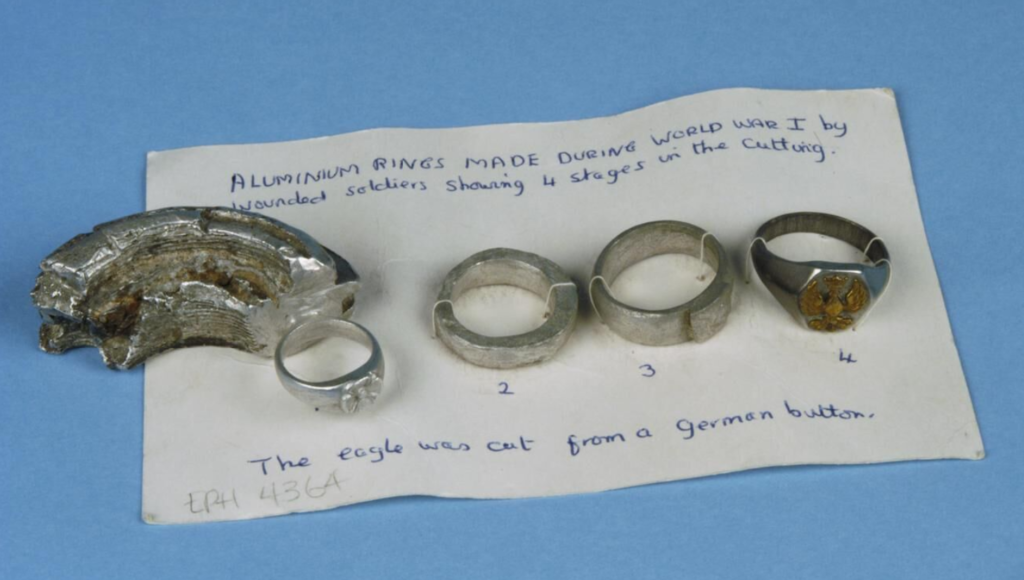 Making jewellery in a time of war:
Four stages showing the making of a ring from an aluminium shell fragment and the insignia from a German uniform button. Made in a hospital ca. 1916.
Imperial War Museum