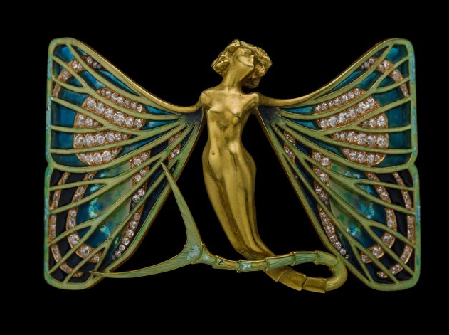 Rectangular brooch formed of a central gold figure of a naked woman with head thrown back and legs terminating in a forked fishtail Her arms have been transformed into large wings set with open backed enamel mimicking butterfly wings, in blue, green, black and white. 