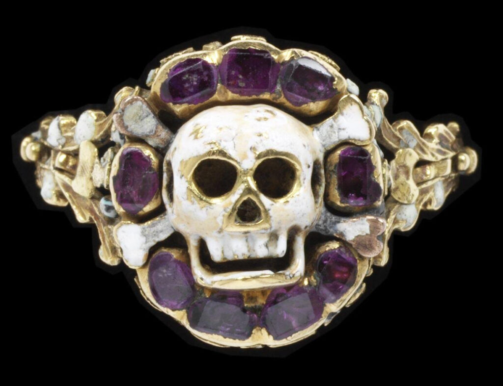 Enamelled gold ring, the bezel in the form of a skull and cross-bones in a border of rubies. The skull is a symbol of death and eternal judgment.  