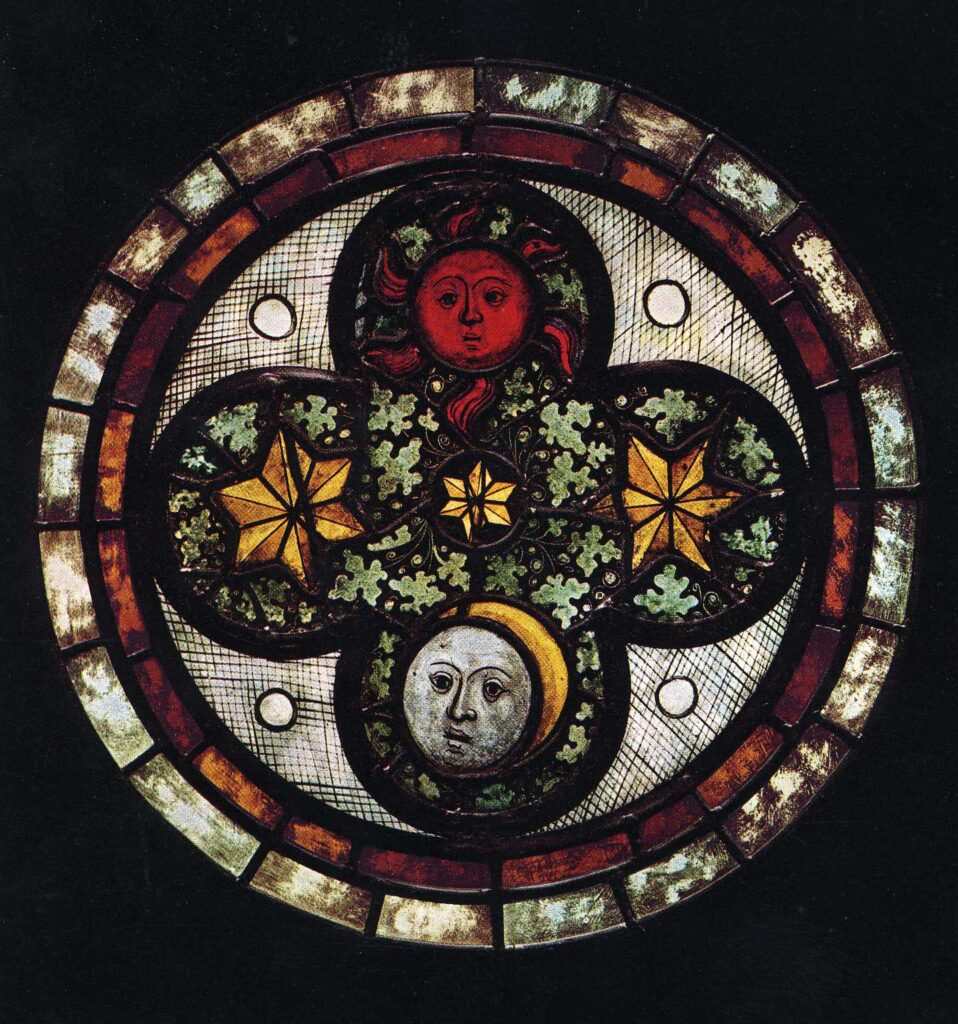 Circular piece of stained glass with a brown glass frame holding a quatrefoil design. The upper petal of the quatrefoil has an image of the sun as a brown/ gold circle with a human face. The centre of the roundel and the two side petals have gold stars surrounded by greenery. The bottom petal shows the moon as a silver circle with a face and on the left of the face is a yellow crescent moon. 