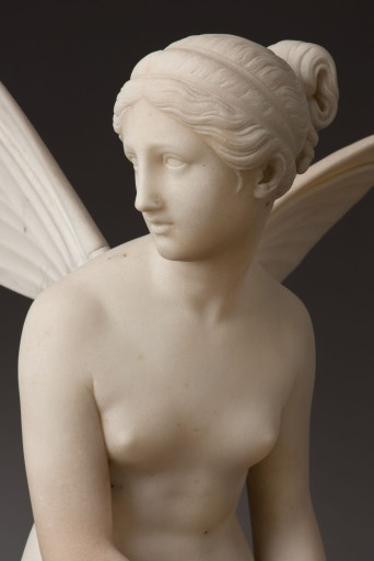 Detail from marble statue of Psyche by Ludwig van Hofer. It shows the head and naked torso of Psyche, sculpted in white marble. She is turning her head to look over her shoulder to the right, her hair is arranged in a chignon on the back of her head. Small wings sprout from her shoulders. 