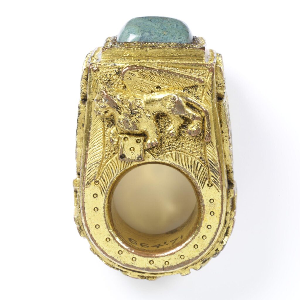 Gilt copper ring with green glass stone. Cast with papal arms on the shoulders. Part of Edmund Waterton's ring collection.