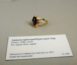 Gold and sapphire ring next to a card gallery label.