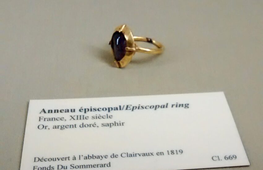 Gold and sapphire ring next to a card gallery label.