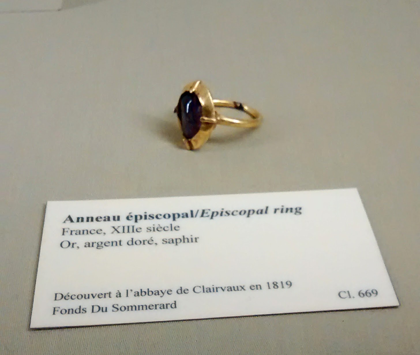 Gold and sapphire ring next to a card gallery label.