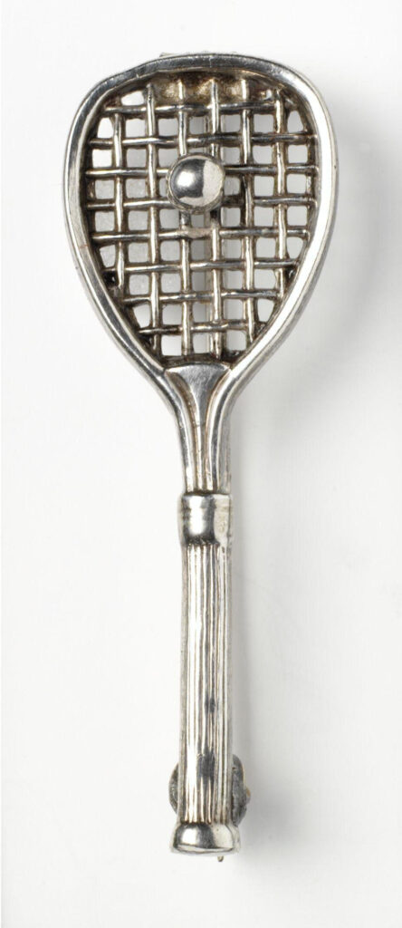 Electroplated silver brooch in the shape of a tennis racket and ball. 