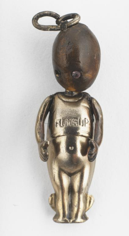 Small gold coloured doll with wooden head. Arms by side with thumbs up and small wings on feet. Lucky token Fumsup charm from World War One. 