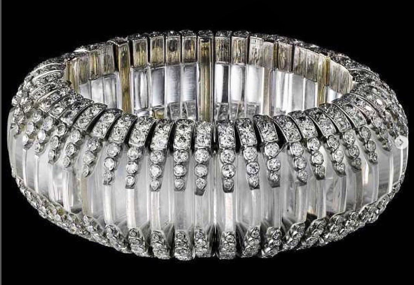 Large bangle made up of rounded slices of rock crystal set side by side and each with a row of diamonds at the top and bottom.