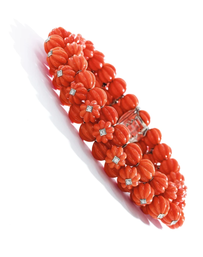 Designed as three rows of carved coral beads, the top row embellished with single-cut diamonds
