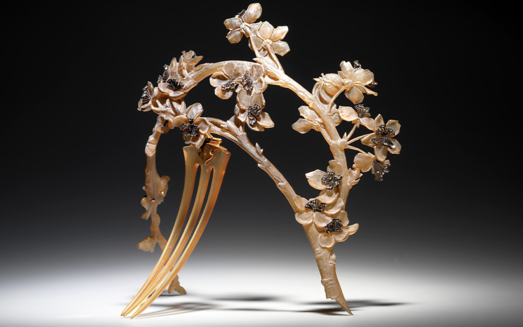 Diadem in the shape of branches of an apple tree covered with carved open blossom. The branches and flowers made of translucent brown horn and the centre of the flowers set with small diamonds. Three pronged horn comb at the base.