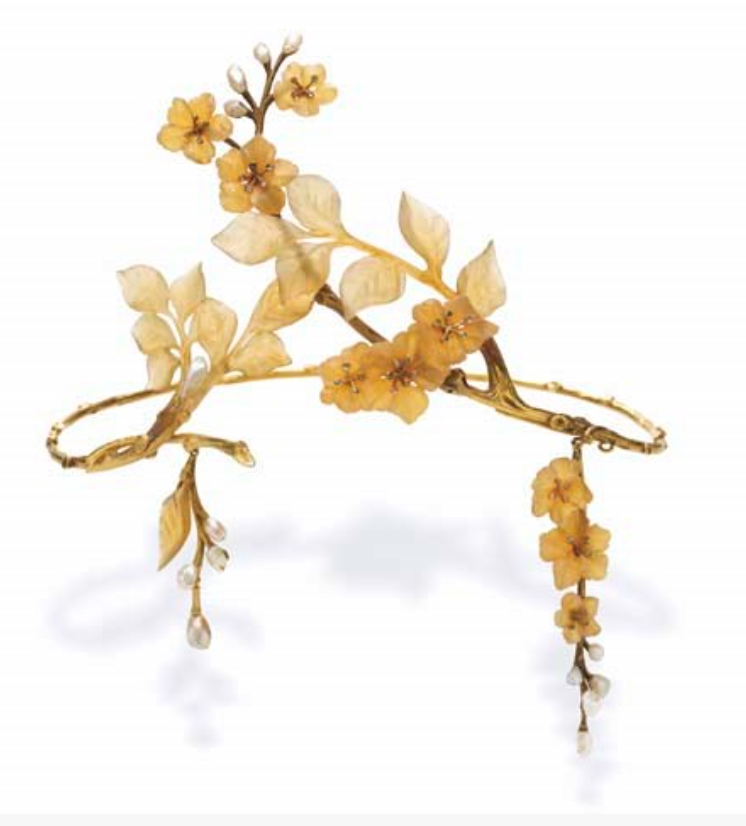 AN ART NOUVEAU HORN AND GOLD TIARA, BY PAUL LIENARD
Designed as carved horn leaves and apple blossoms with collet-set diamond pistils, to the textured gold branches and twigs, enhanced by baroque pearl buds, suspending two detachable clusters of flowers and leaves of similiar design, mounted in gold, circa 1900,