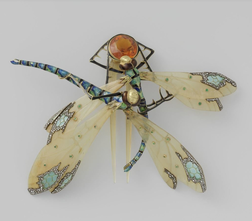 Hair comb of horn, gold, emerald, diamond, citrine, and enamel. Two dragonflies, with their wings partially overlapping, fight over prey (a smoky citrine set in gold). The wings are of horn, the bodies of gold. The two-pronged comb is attached at the back by means of a golden hinge.